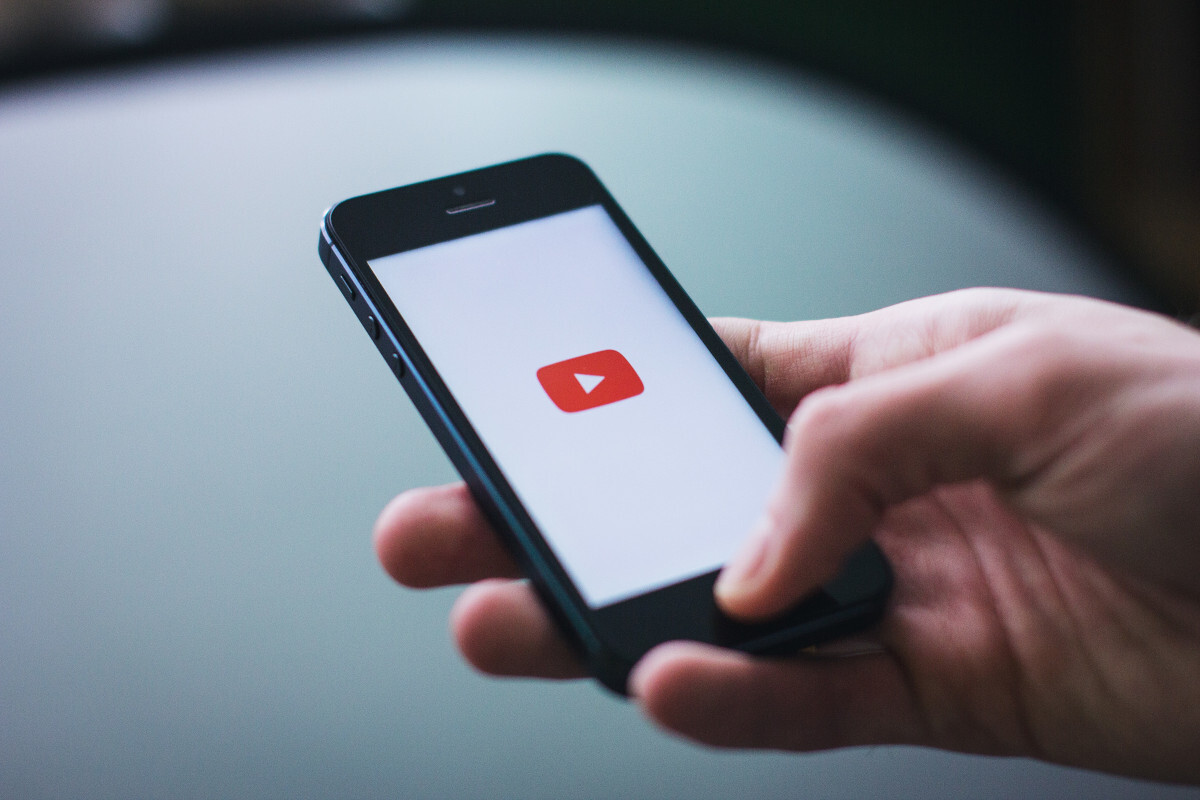 Smartphone mit einem YouTube Logo und weißem Hintergrund auf dem Startscreen