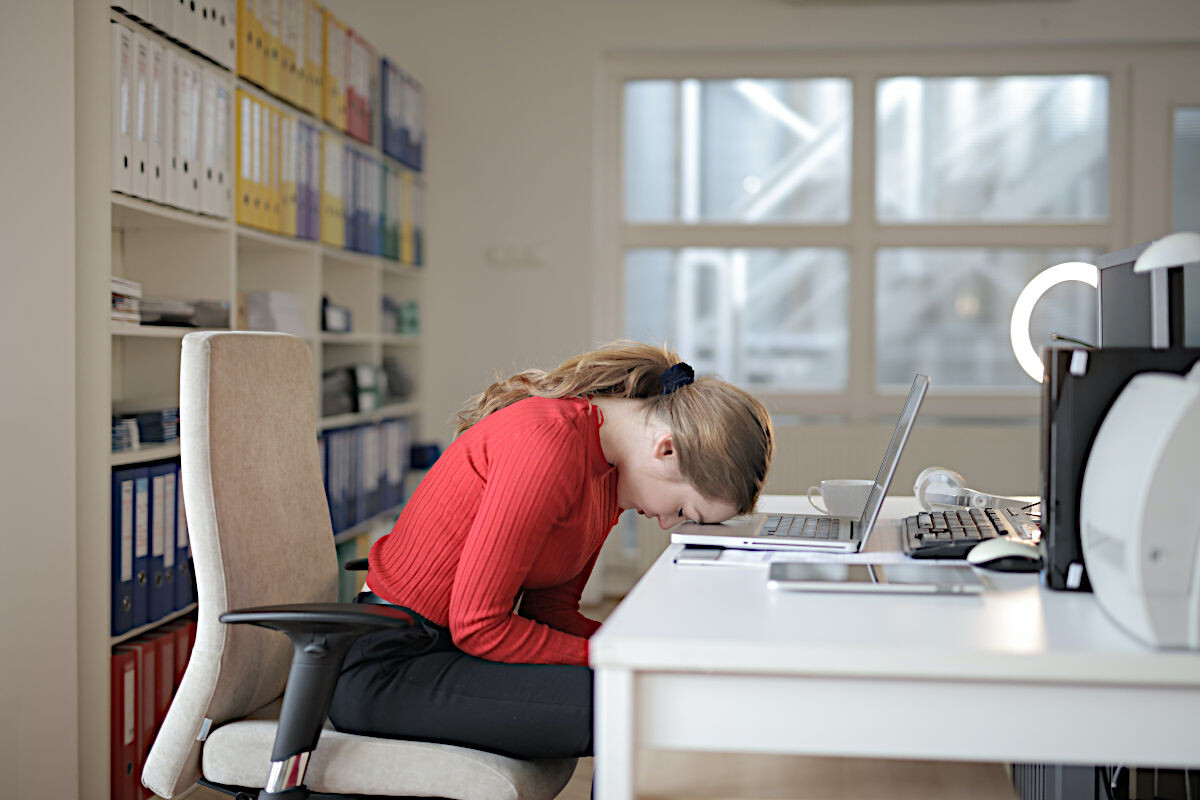 Dame mit dem Kopf auf dem Tisch durch Frust bei der Remote Work im Home Office