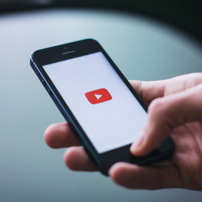 Smartphone mit einem YouTube Logo und weißem Hintergrund auf dem Startscreen