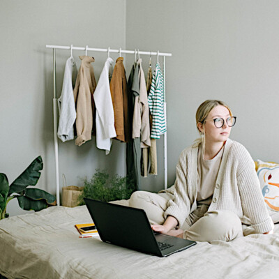 Dame sitzt mit Laptop in ihrem Bett im Schlafzimmer