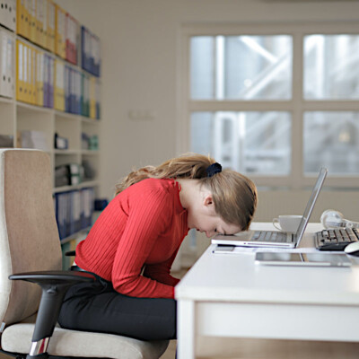 Dame mit dem Kopf auf dem Tisch durch Frust bei der Remote Work im Home Office